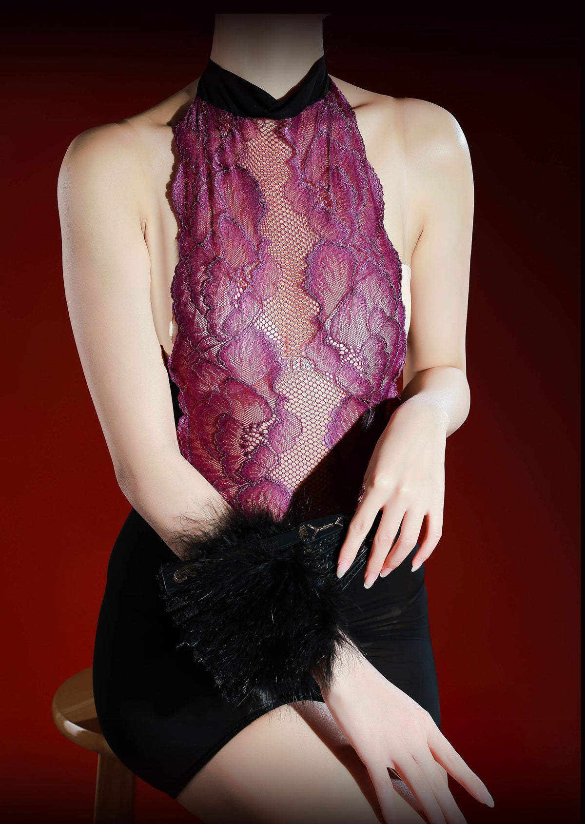IOO&SILK plum lace halter one-piece, seated with a black feathered fan across the lap